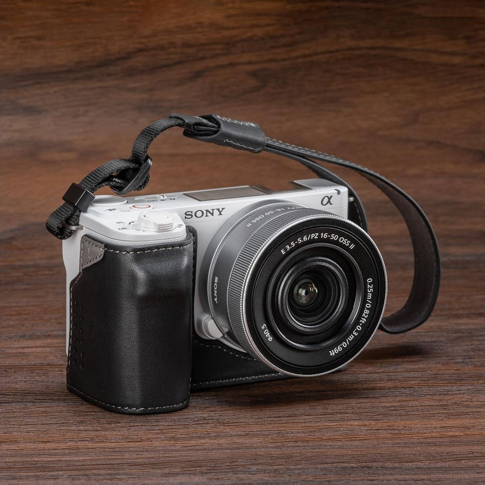A white Sony camera with a black leather case and strap.