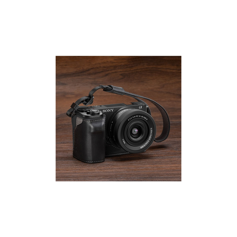 Black Sony camera with lens and strap on a wooden surface.