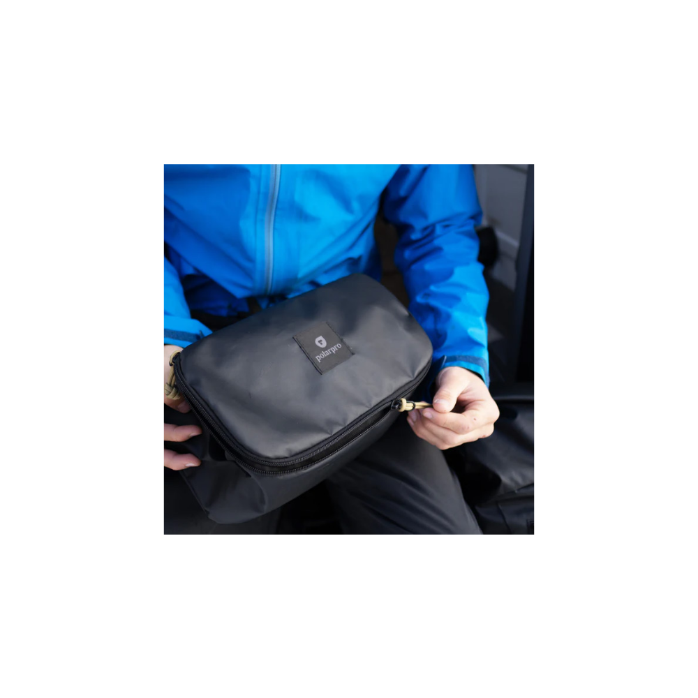 A person in a blue jacket holds a black bag with a zipper.