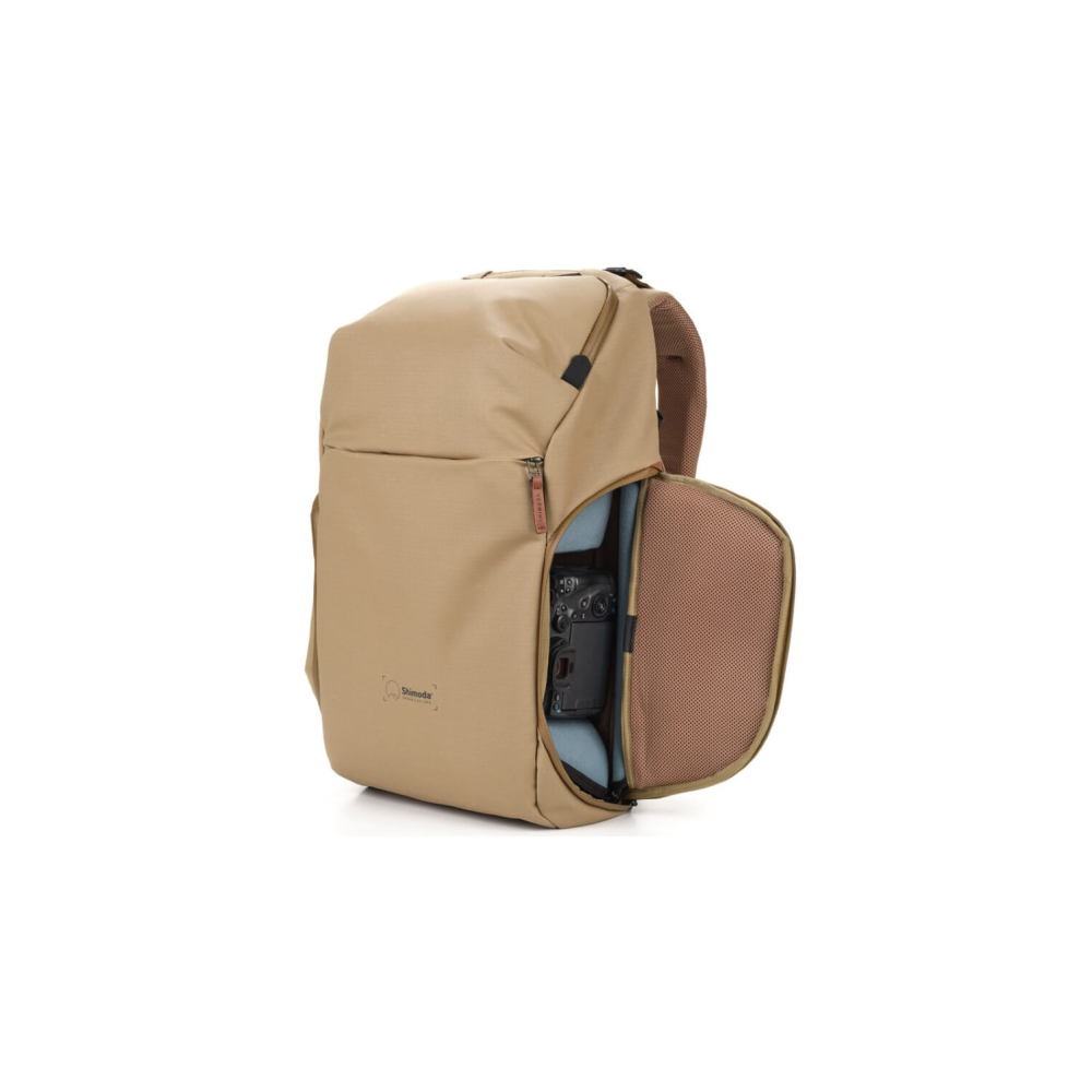 A tan backpack with an open side flap revealing a camera inside.