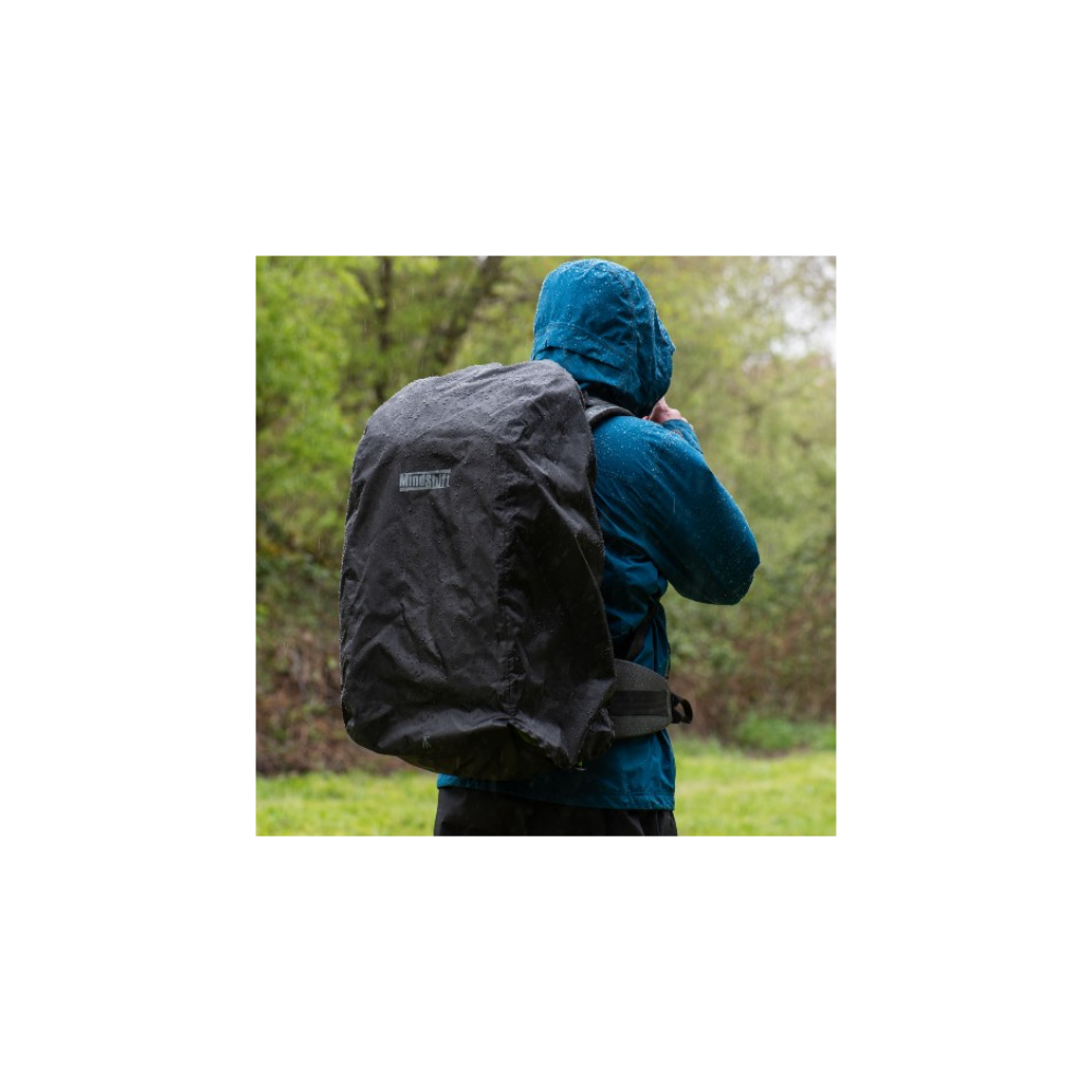 Persoon met blauwe jas en rugzak met regenhoes in de regen.