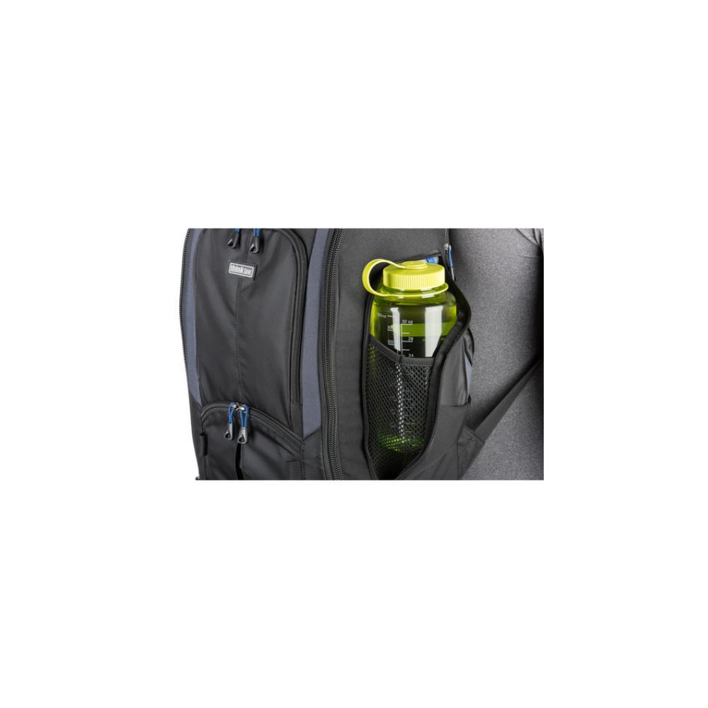 A green water bottle is in the mesh side pocket of a black backpack.