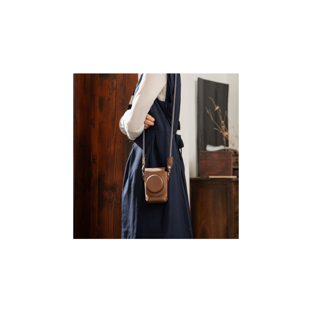Person in navy apron dress over white shirt with brown camera case.