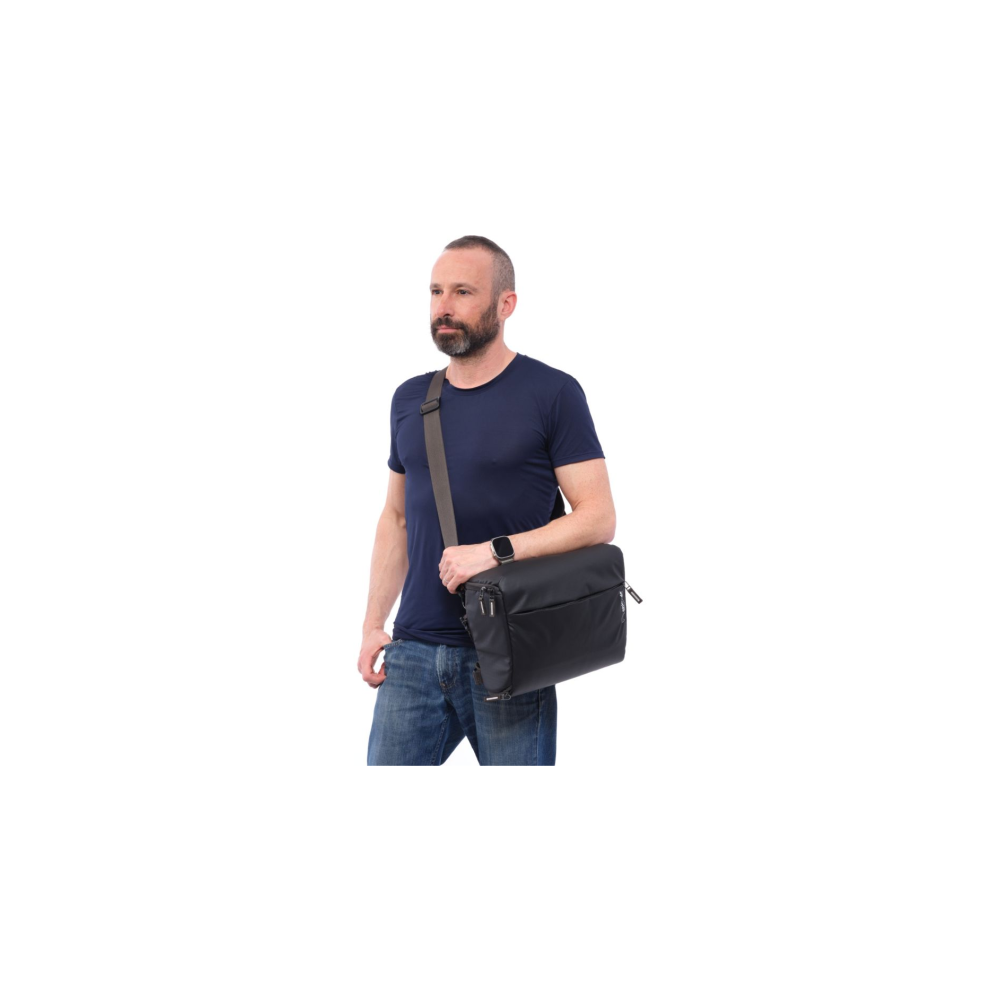Een man met een baard draagt een donkere tas over zijn schouder.