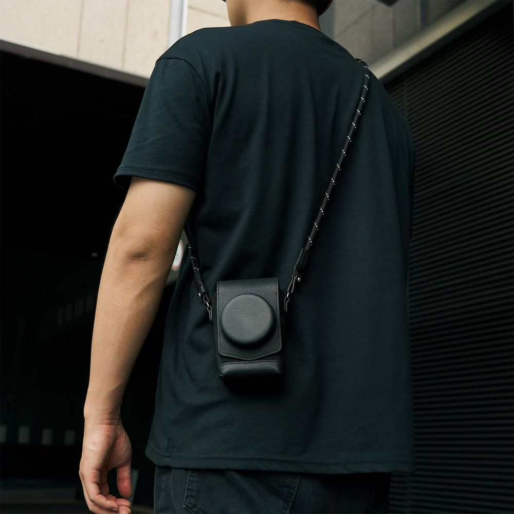 Man in zwart t-shirt draagt zwarte cameratas crossbody.