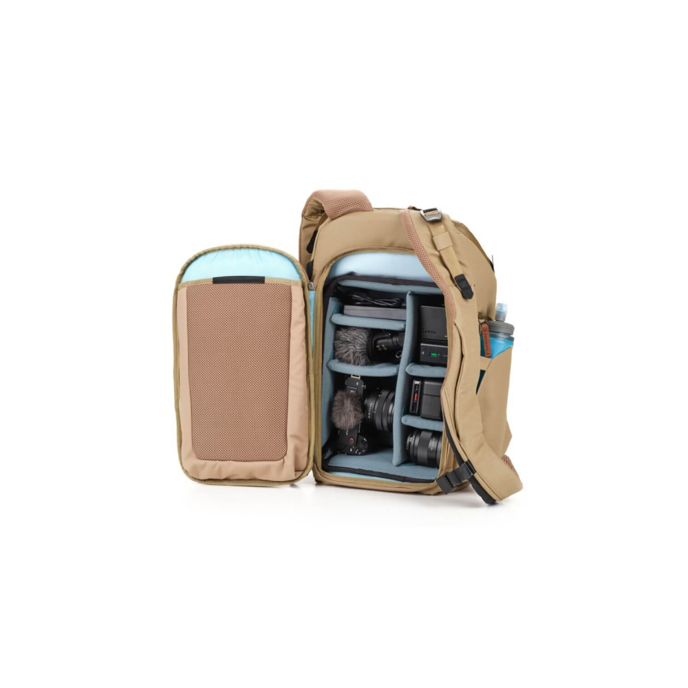Open tan camera backpack with various gear like cameras and microphones inside.