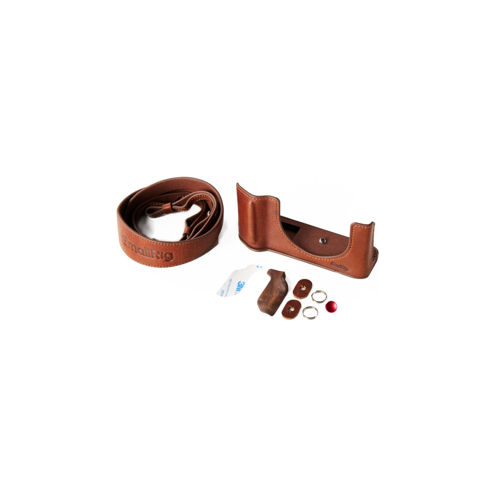 Brown leather camera accessories: strap, case, wood grip, tape, rings, red button.