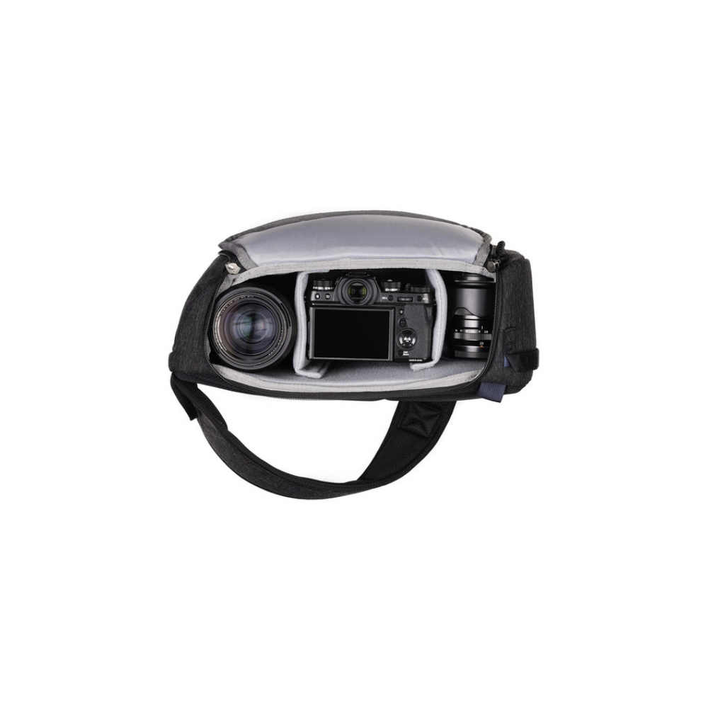 Een zwarte cameratas met een camera, een lens en nog een lens erin.