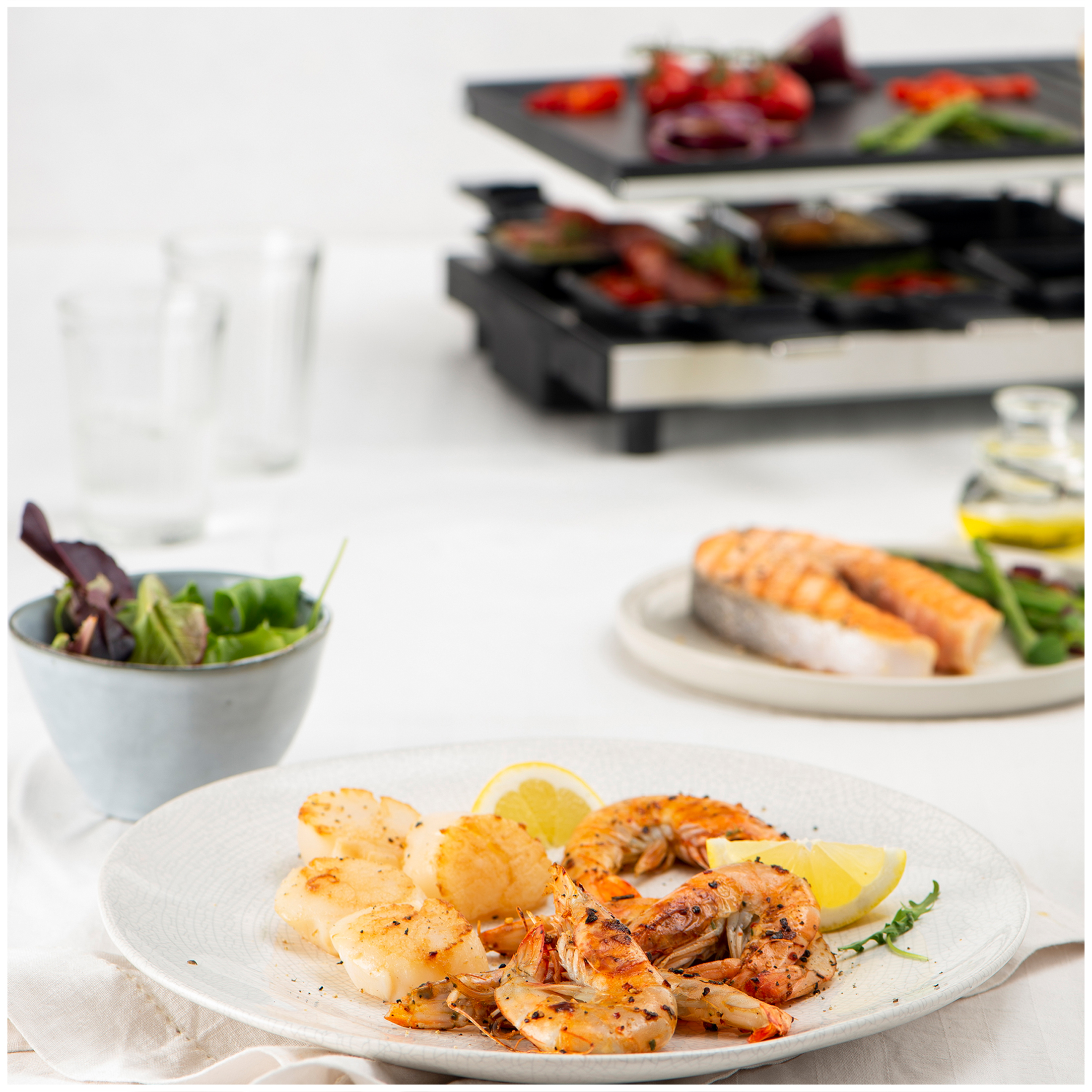 Grilled shrimp and scallops on a plate with lemon and salad in the background.