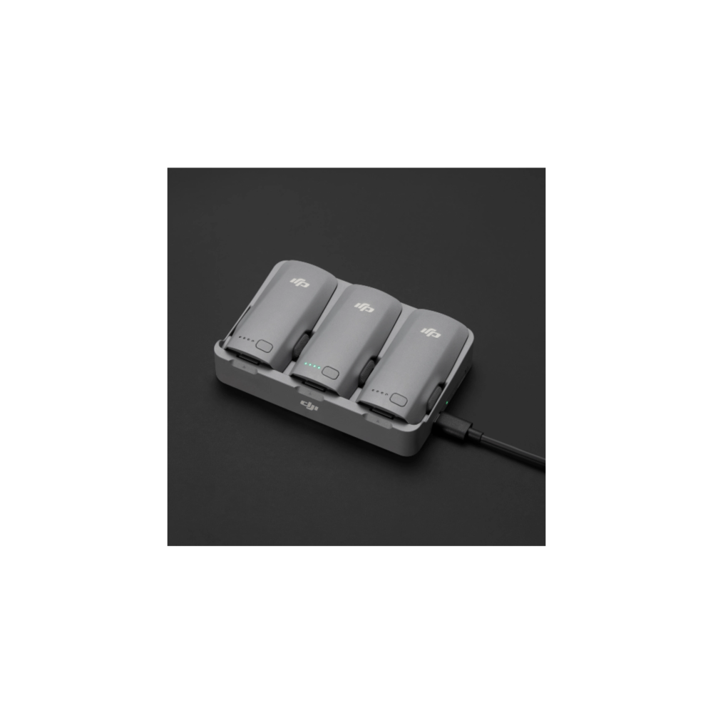 Tre batterie per droni grigie in carica in un hub di ricarica con cavo USB.