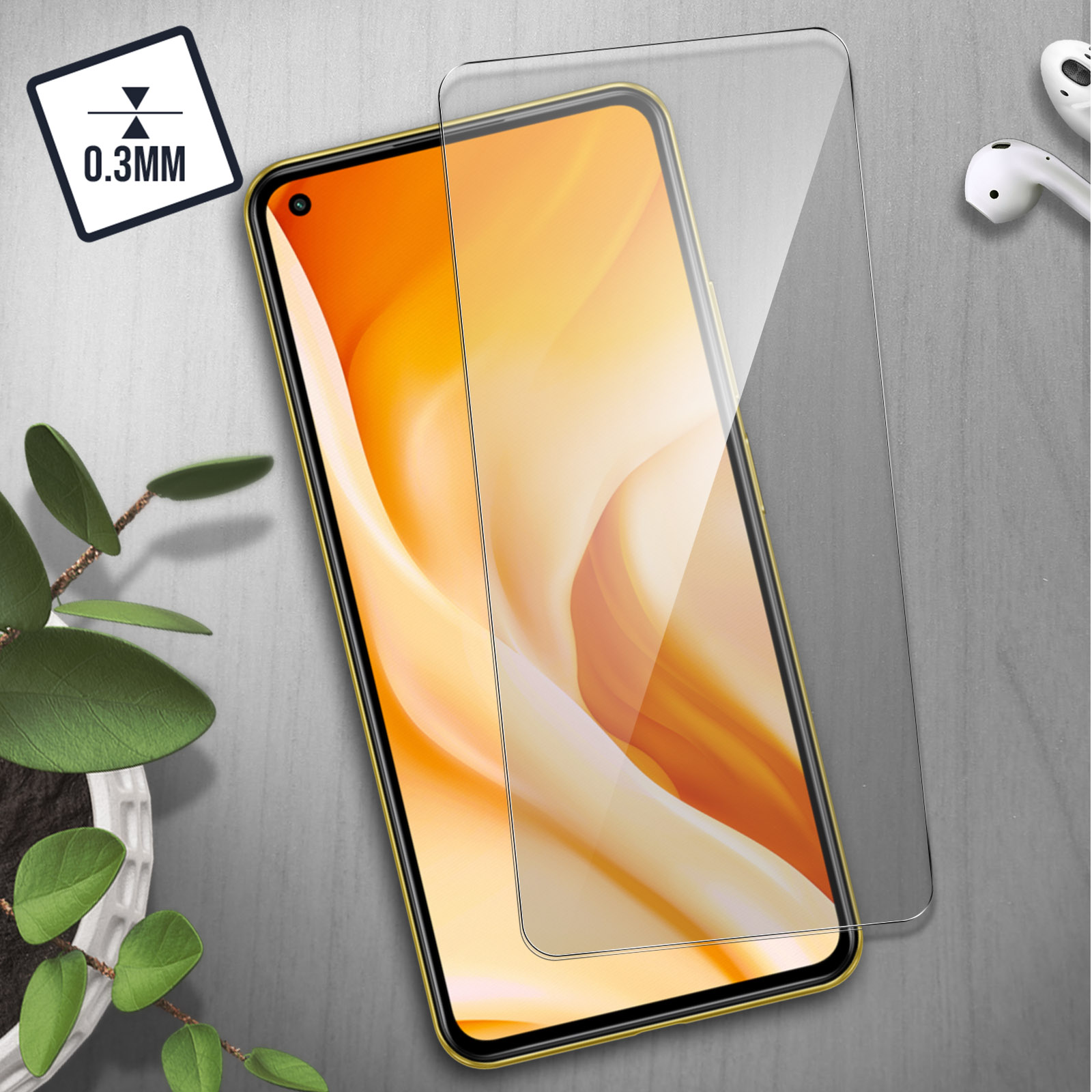 Un smartphone avec un protecteur d'écran à côté, des écouteurs et une plante.