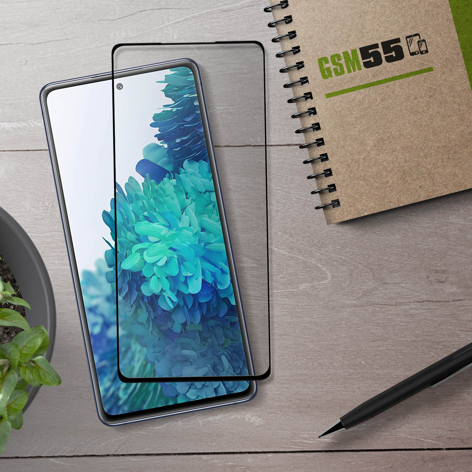 Een smartphone met schermprotector, een notitieboek en een pen op houten achtergrond.
