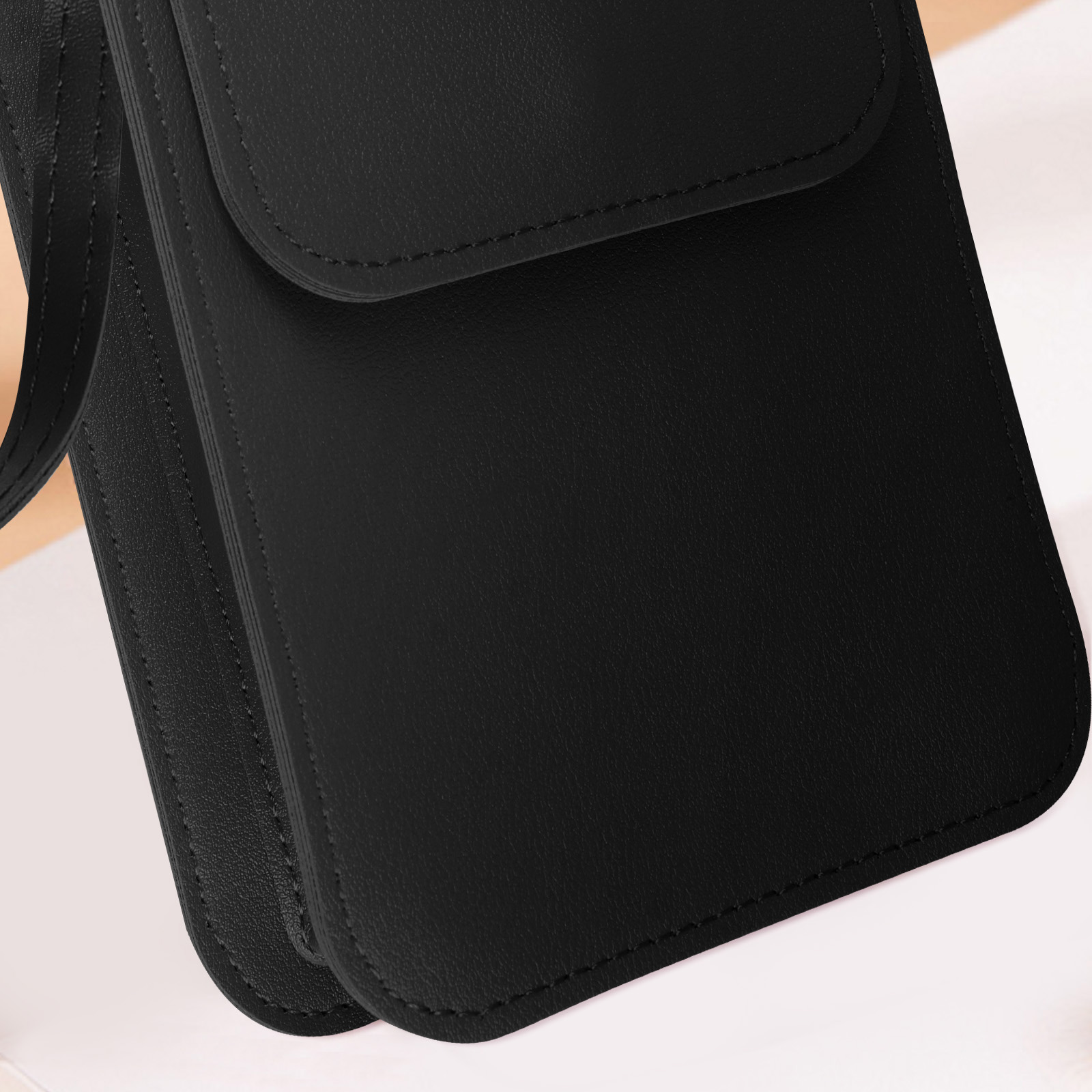 Een zwarte leren tas met stiksels en een riem, van dichtbij.