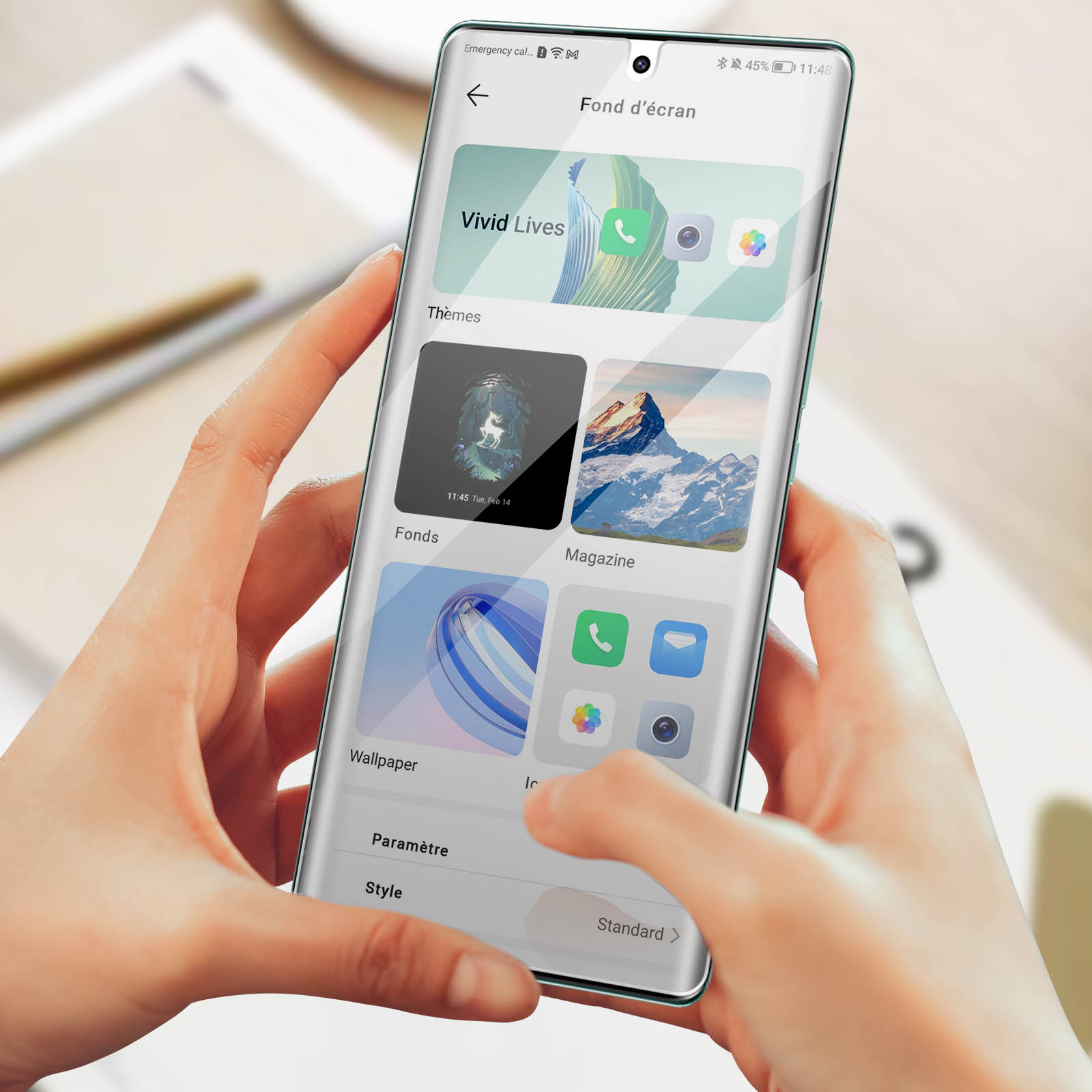 Une personne tient un smartphone affichant une application de personnalisation d'écran.