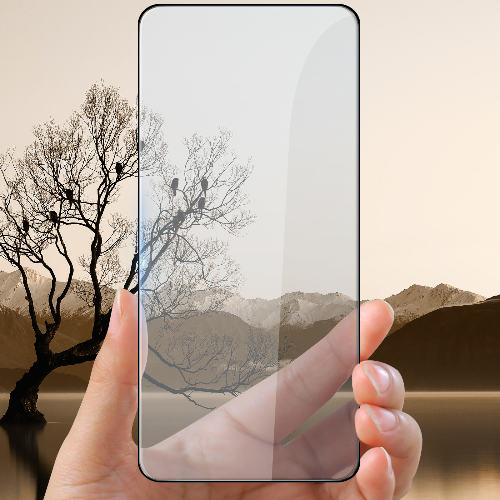 Mano che tiene il telefono davanti al paesaggio con albero e montagne.