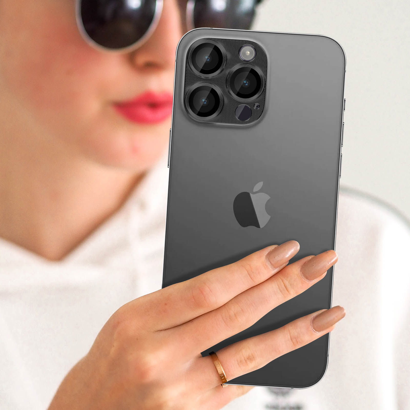 Une personne portant des lunettes de soleil tient un iPhone gris à trois caméras.