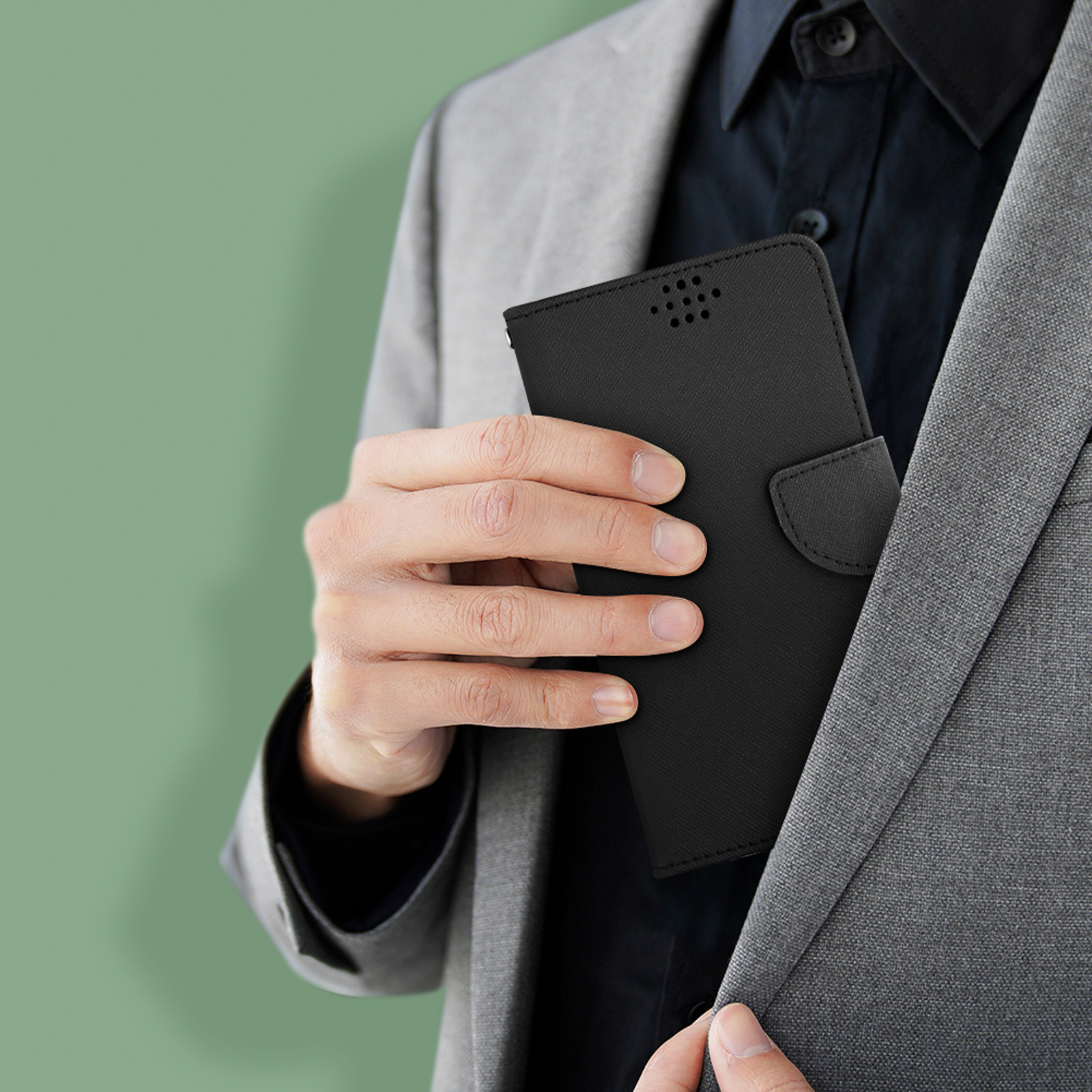 Un homme en costume gris met un étui noir pour téléphone dans la poche de sa veste.