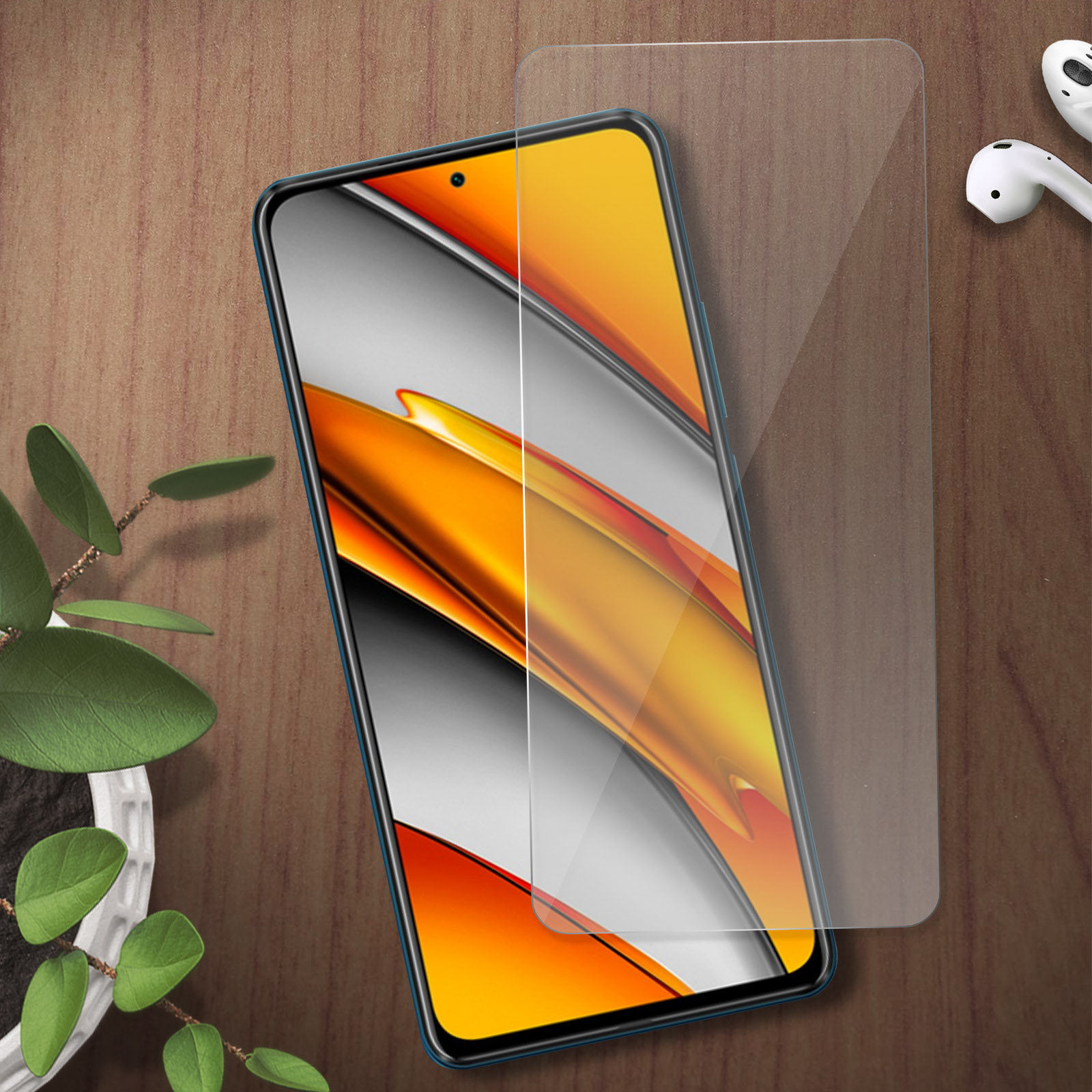 Uno smartphone con pellicola protettiva, auricolari e pianta su sfondo di legno.