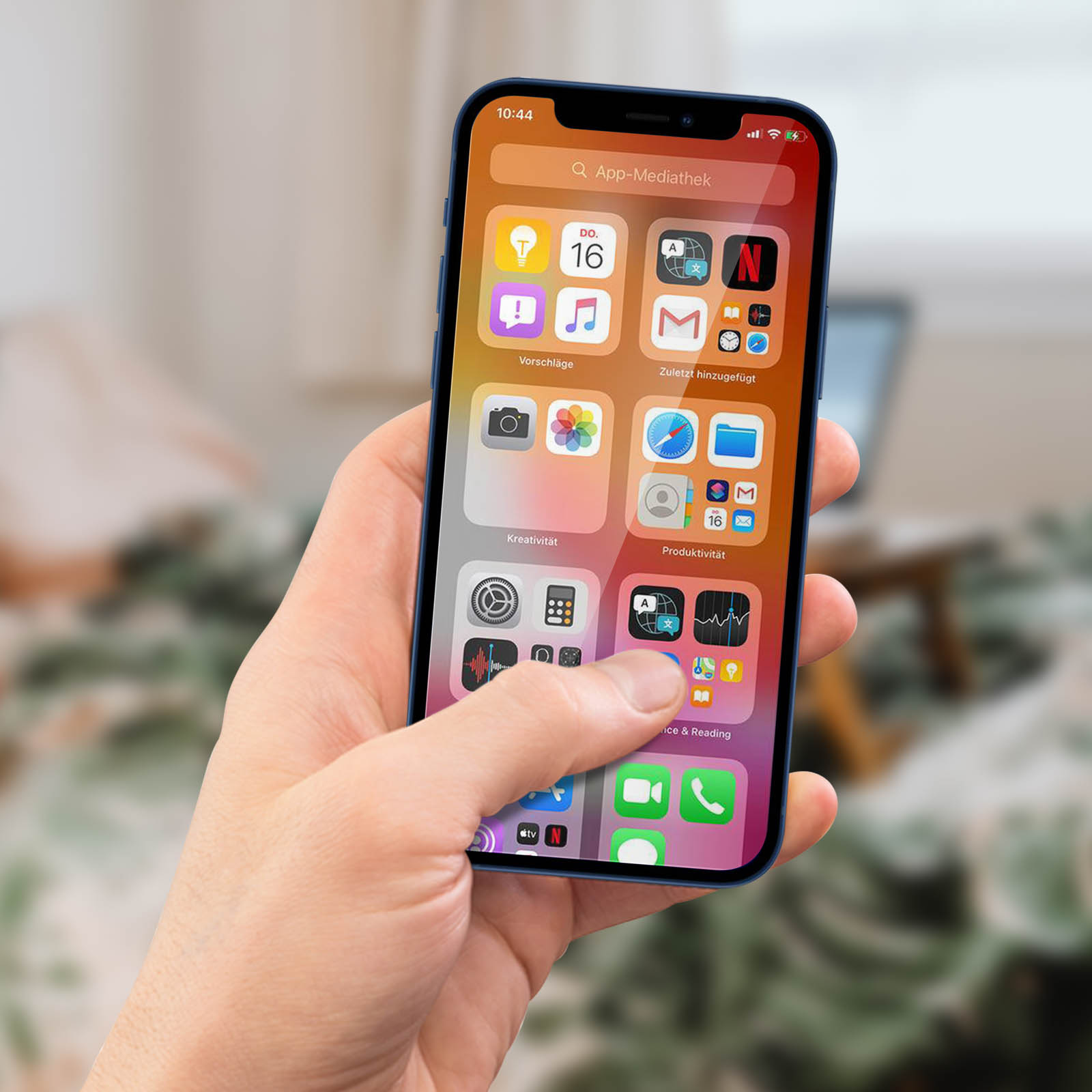 Una mano tiene uno smartphone con la schermata principale, la data è il 16.