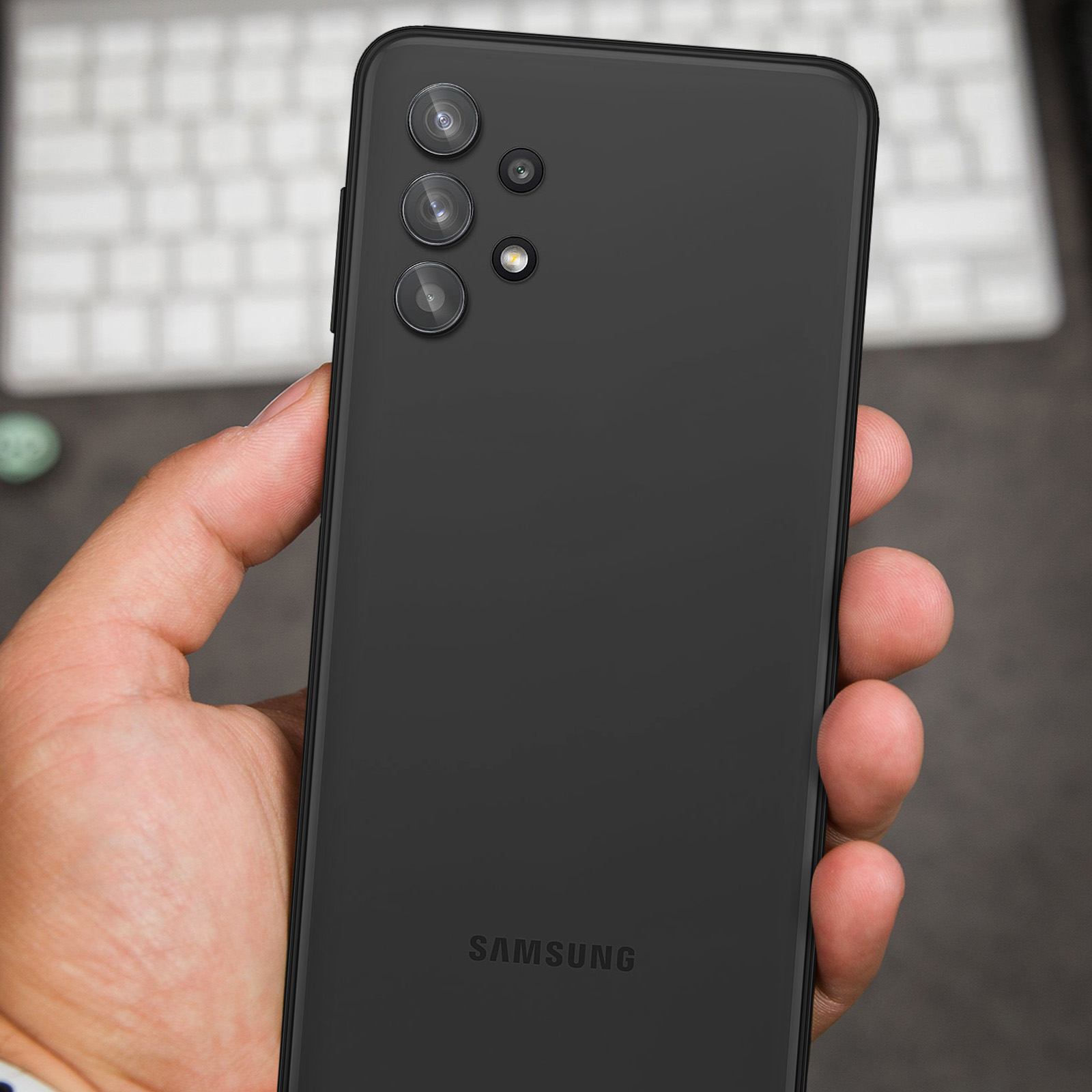 Une personne tient un smartphone Samsung noir avec quatre caméras.