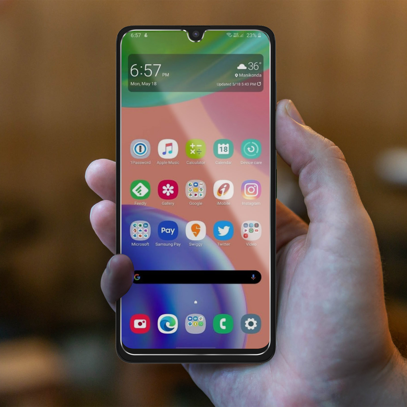 Una mano tiene un telefono cellulare che mostra app e l'ora. Sfondo sfocato.