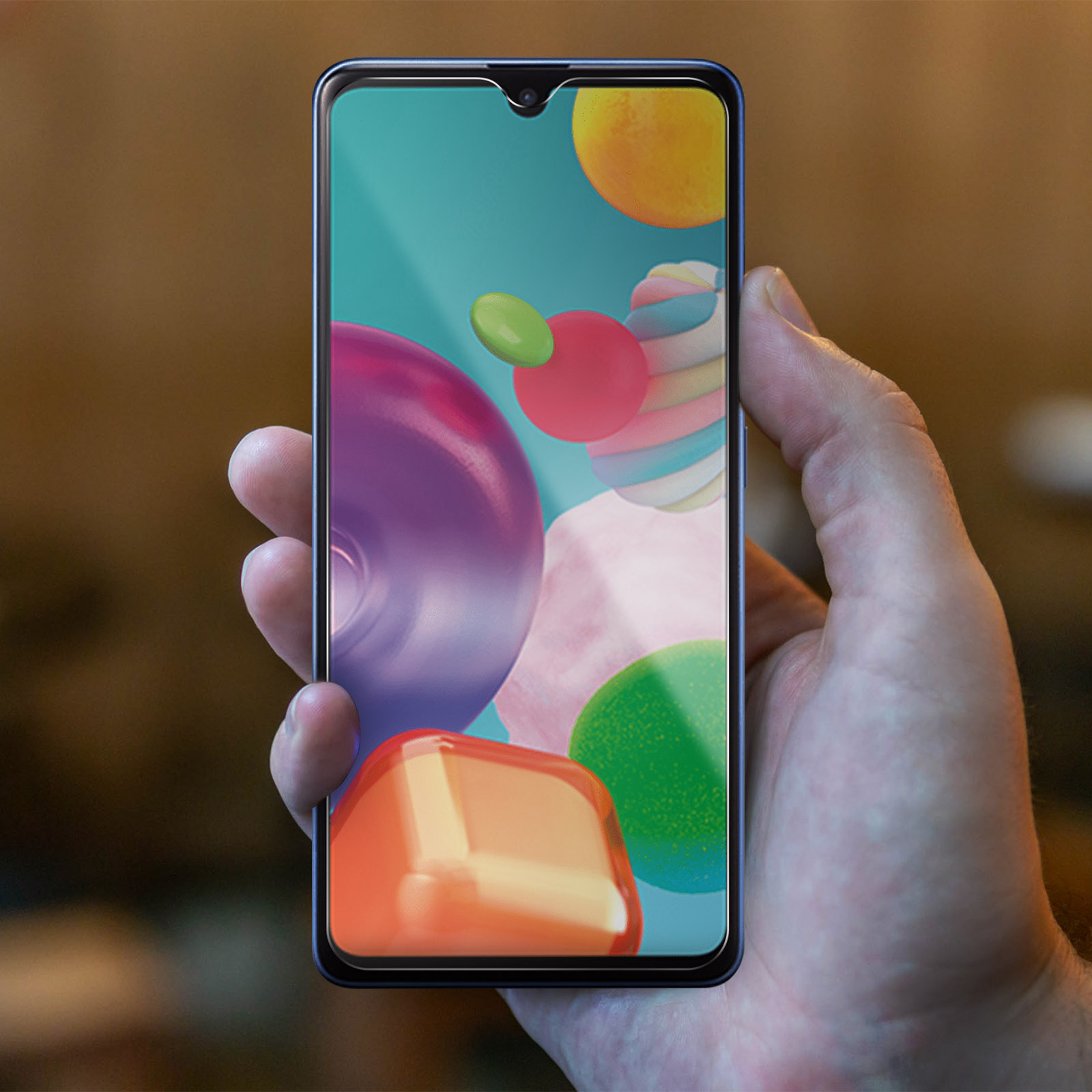 Mano che tiene uno smartphone con forme astratte colorate sullo schermo.