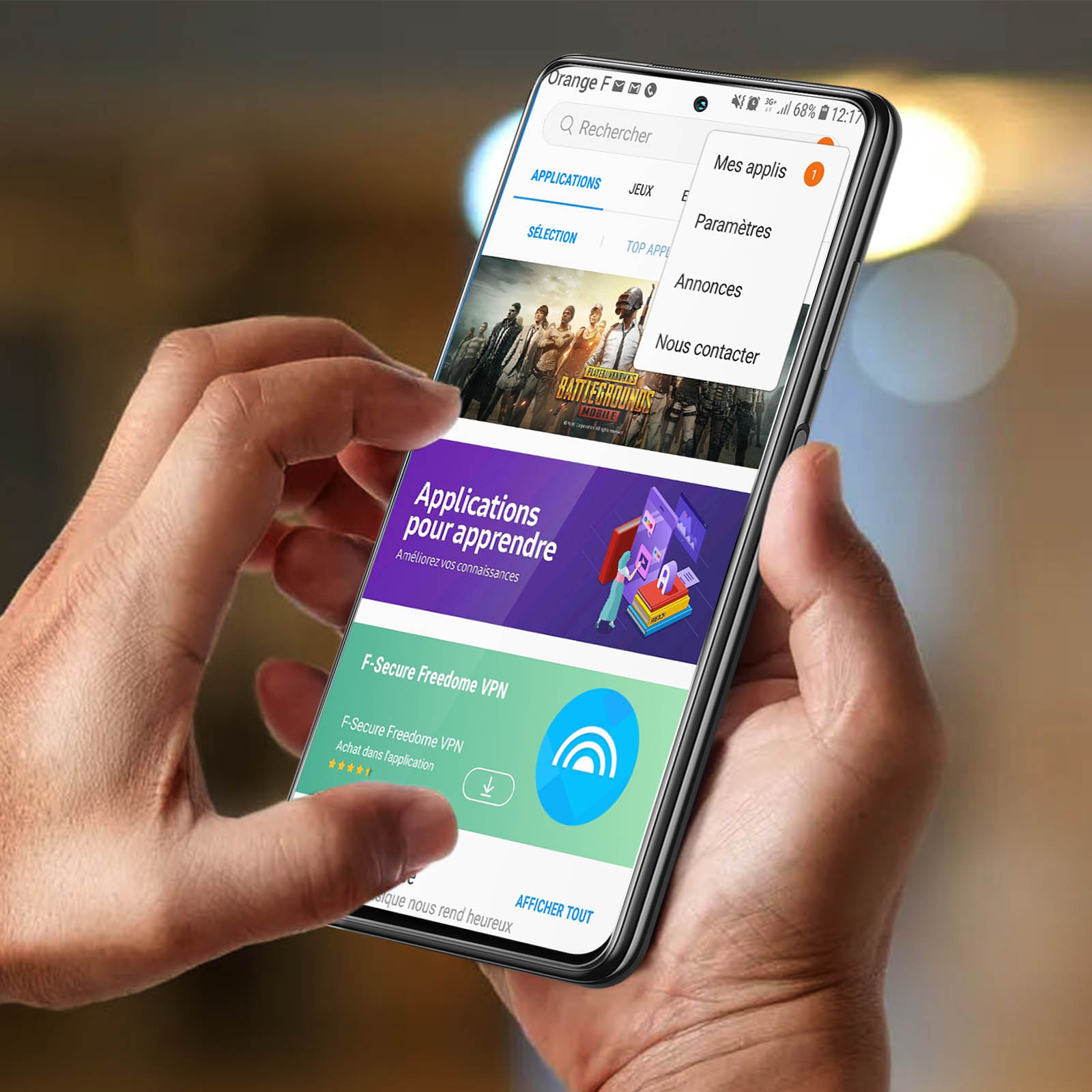Une main tient un smartphone affichant une liste d'applications avec jeux et VPN.