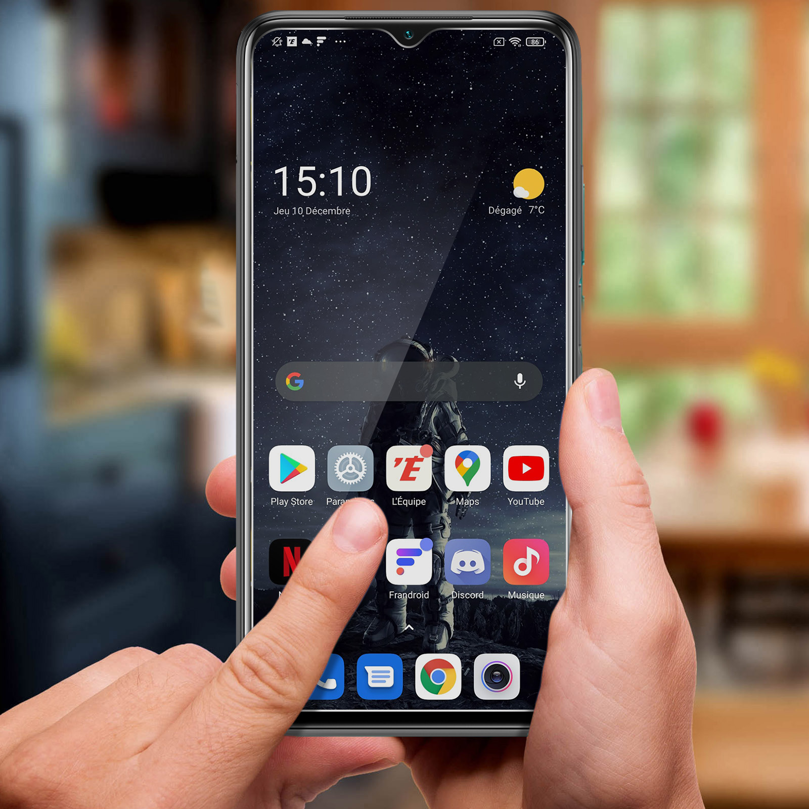 Una mano tiene uno smartphone con sfondo astronauta. App visibili sullo schermo.