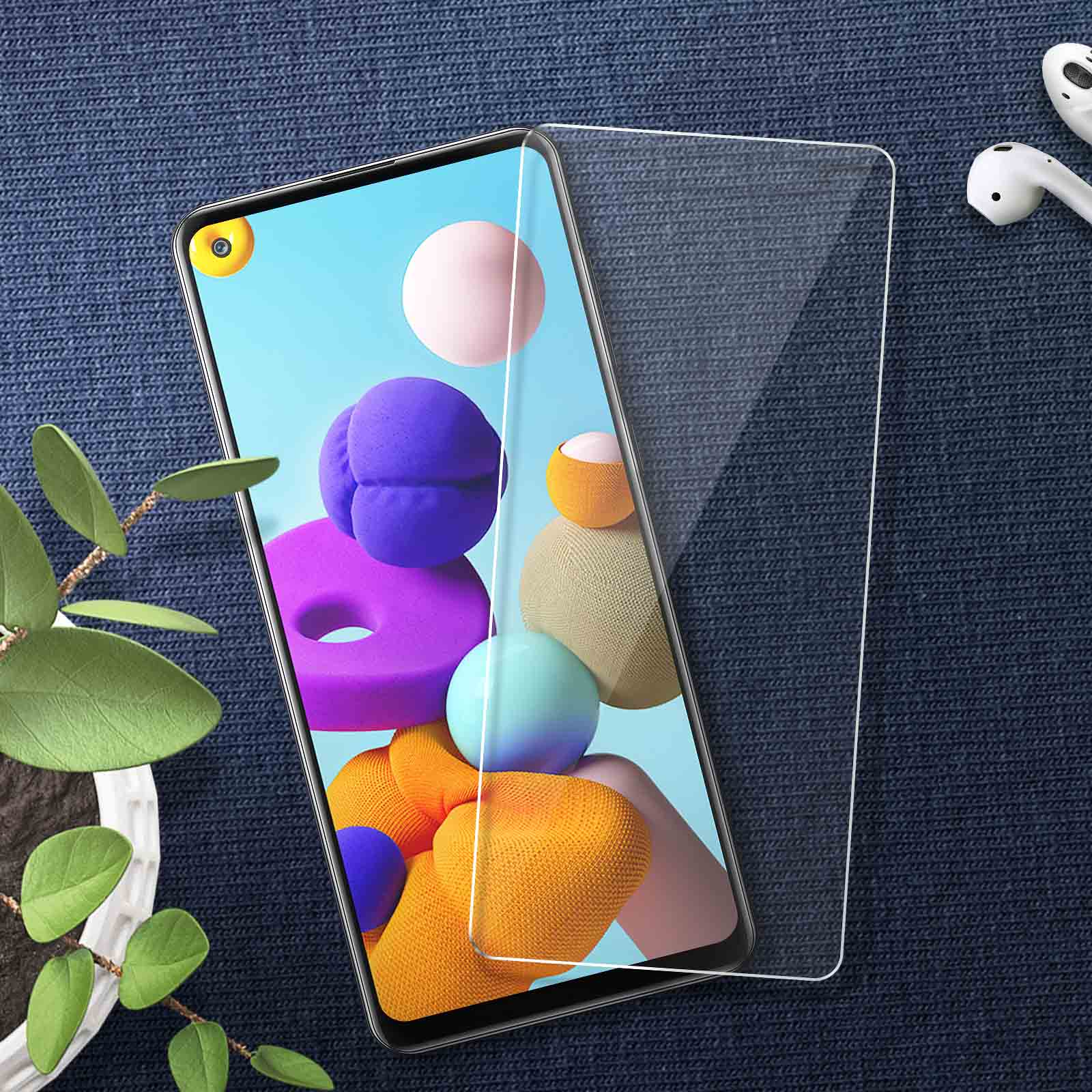 Un smartphone avec protection d'écran sur tissu bleu. Des écouteurs blancs sont à côté.