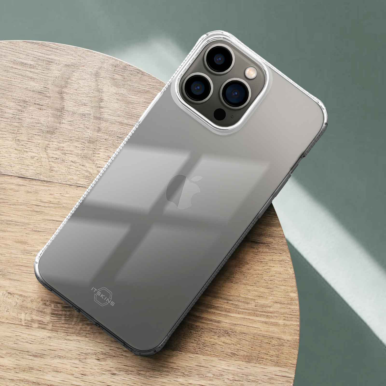 Una cover trasparente per telefono giace su un tavolo di legno con sfondo blu.
