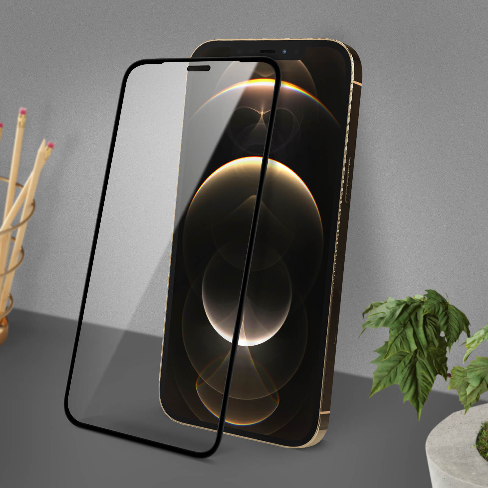 Een gouden smartphone-scherm met een beschermglas ervoor, potloden en een plant ernaast.