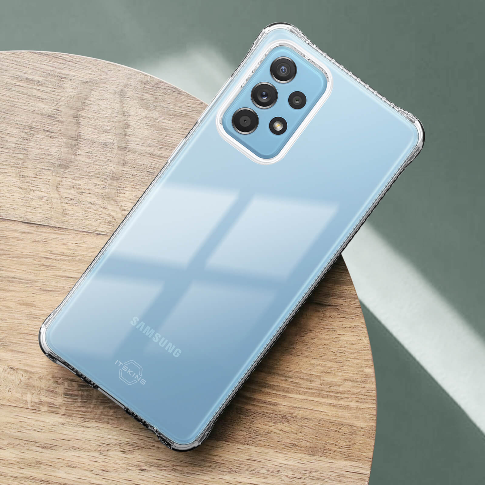 Un telefono Samsung azzurro in custodia trasparente su un tavolo di legno.