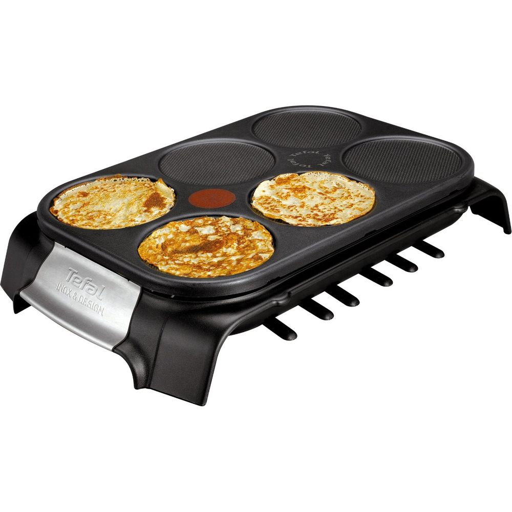 Une crêpière noire avec quatre surfaces de cuisson rondes, cuisant des crêpes.