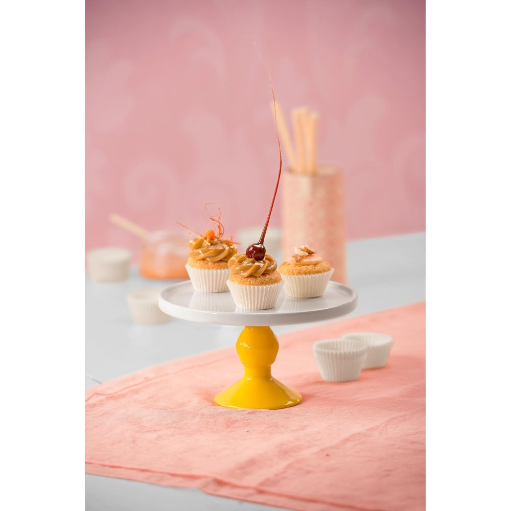 Drei Cupcakes mit Karamellglasur und Kirsche, auf einem gelben Kuchenständer.