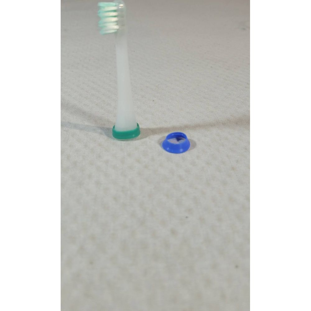 Zahnbürstenkopf mit grünem Ring und blauer Kappe auf kariertem Hintergrund.