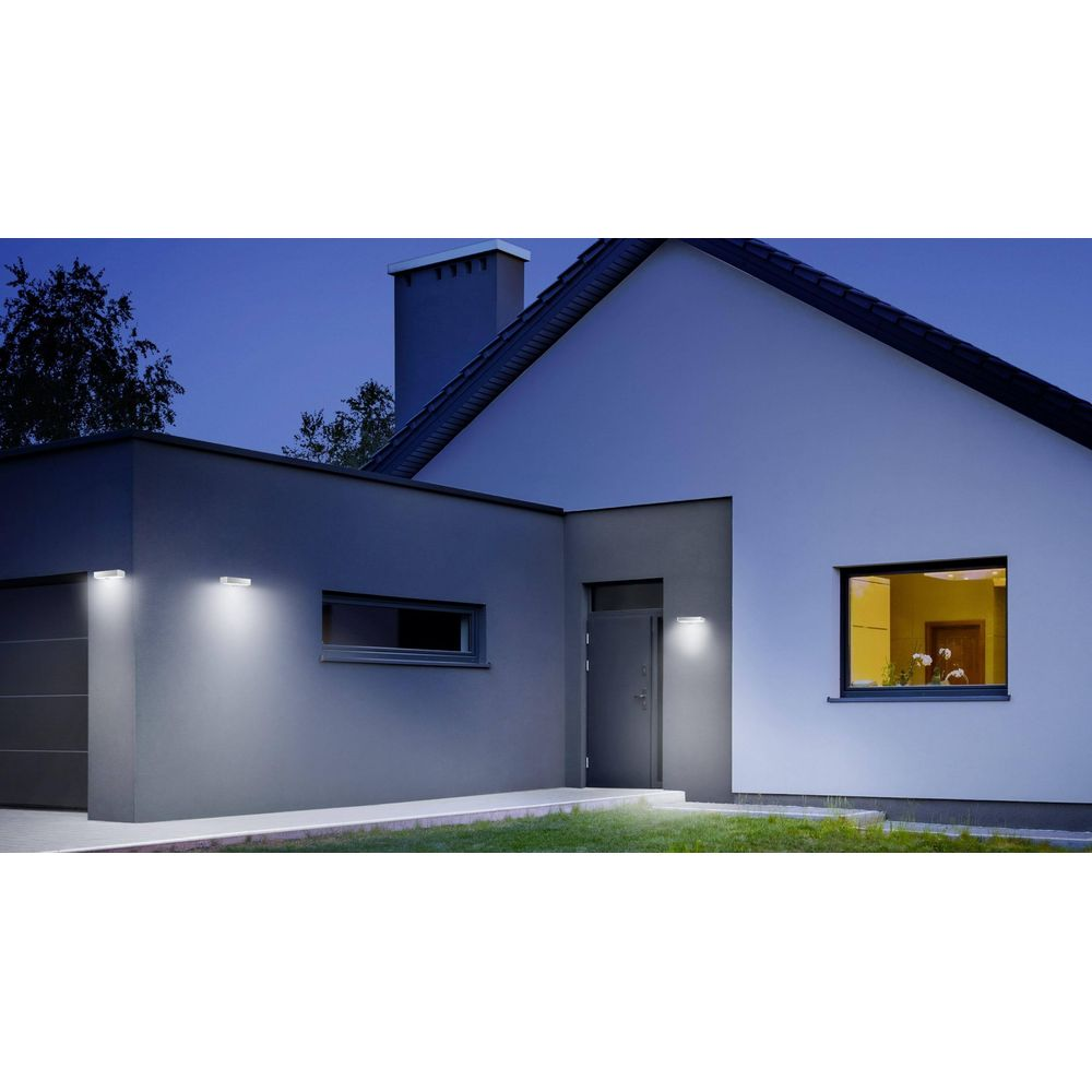 Modernes Haus bei Nacht mit Außenbeleuchtung, Fenstern und Tür.
