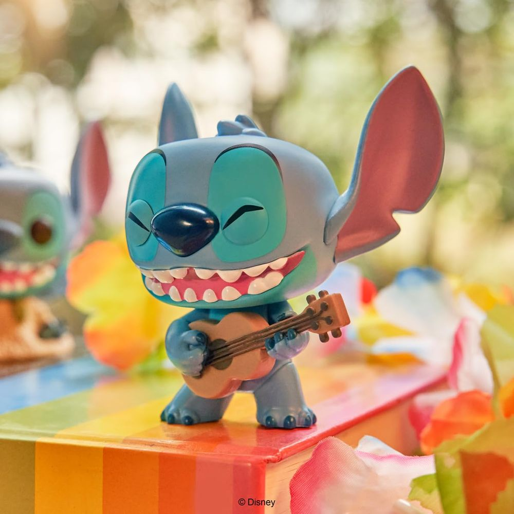 Une figurine de Stitch joue du ukulélé sur un livre coloré, entourée de fleurs.