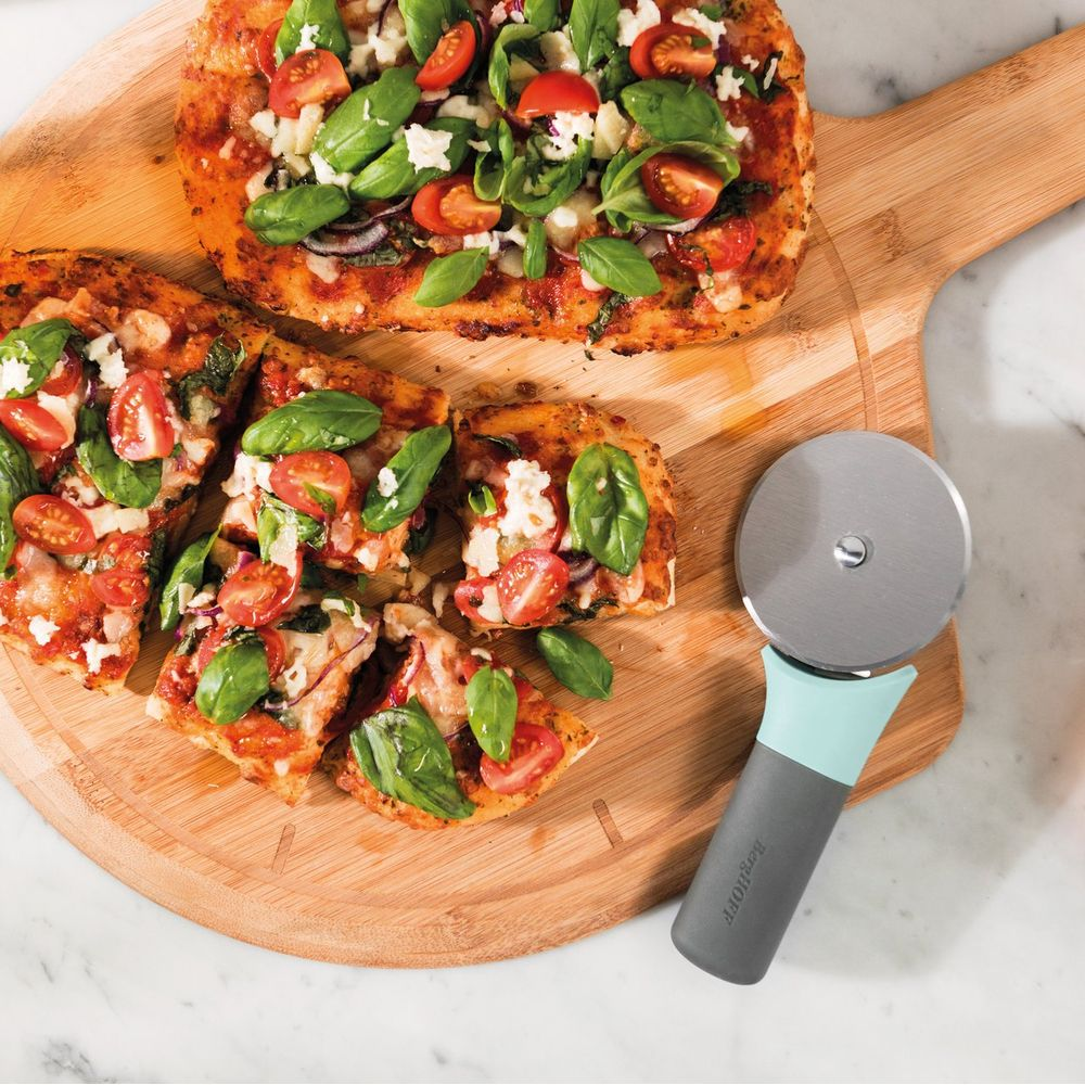 Two rectangular pizzas on a wooden board with a pizza cutter.