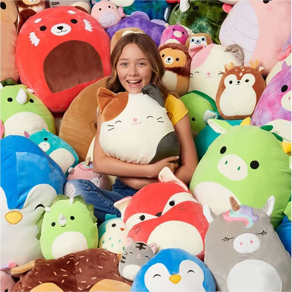 Une fille serre un coussin de chat, entourée de nombreuses peluches colorées.