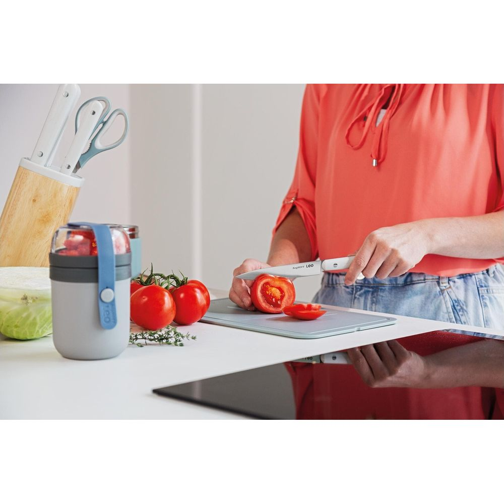 Een persoon snijdt tomaten op een snijplank in een keuken.