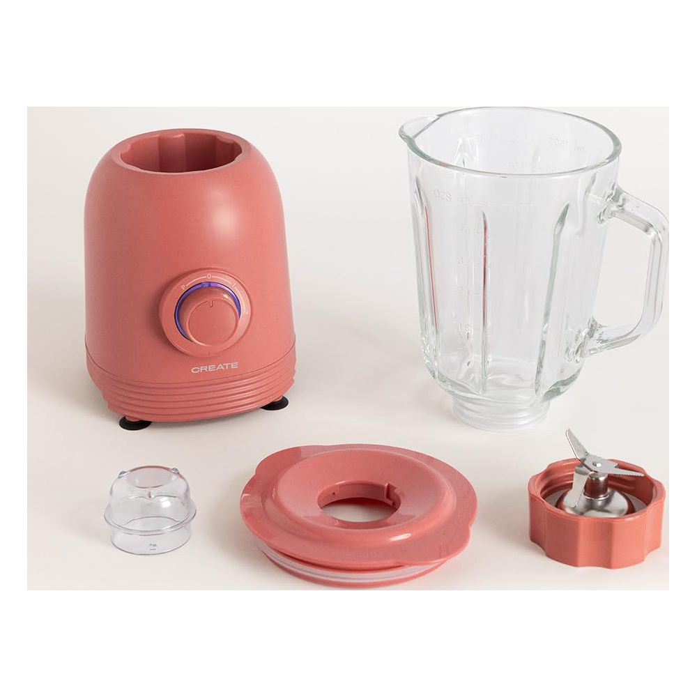 Ein pinker Mixerfuß mit Bedienelement, Glaskrug, Deckel, Messbecher und Klingeneinheit.