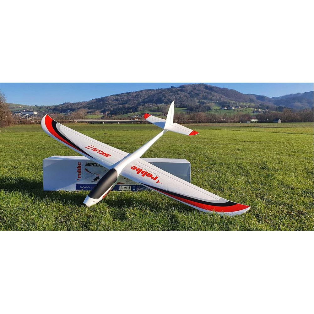 Un planeur RC blanc avec des accents rouges repose sur un terrain vert.