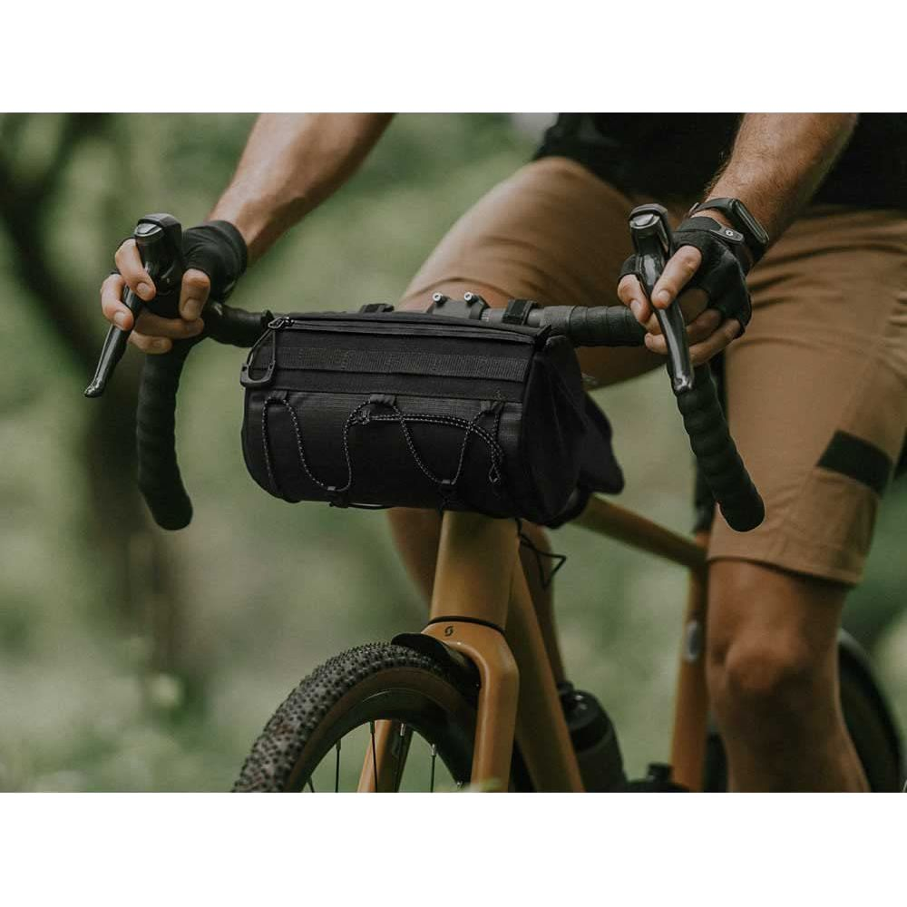 Mann auf Fahrrad mit schwarzer Lenkertasche, braunen Shorts.