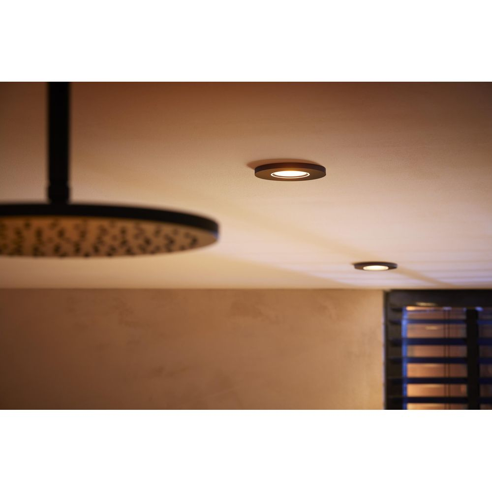 Inbouwspots verlichten een moderne badkamer met een grote douchekop.