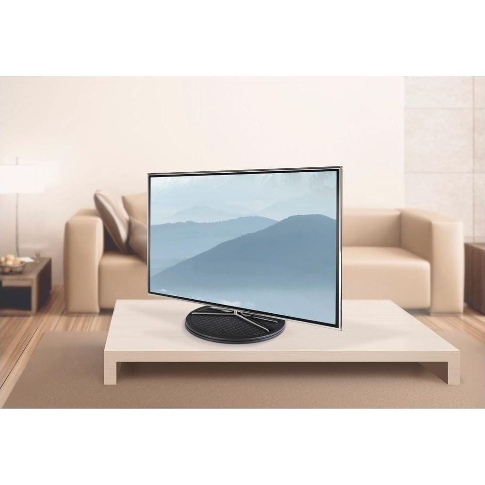 Una TV moderna su un tavolo di fronte a un divano, che mostra un paesaggio montano.