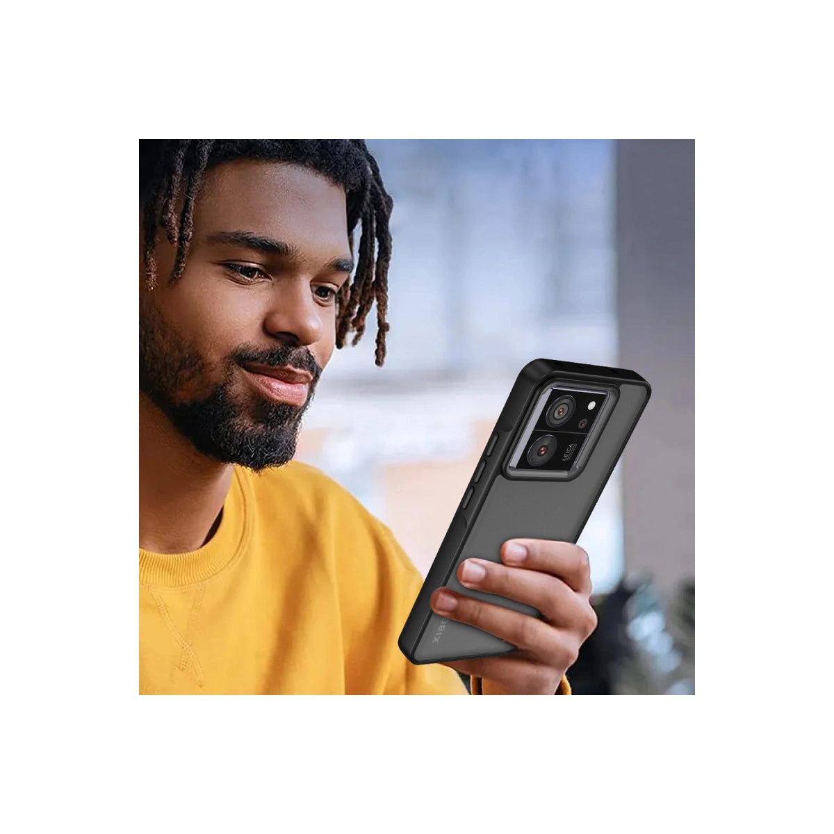 Sarı kazaklı, dreadlock'lu adam siyah kılıflı bir akıllı telefon tutuyor.