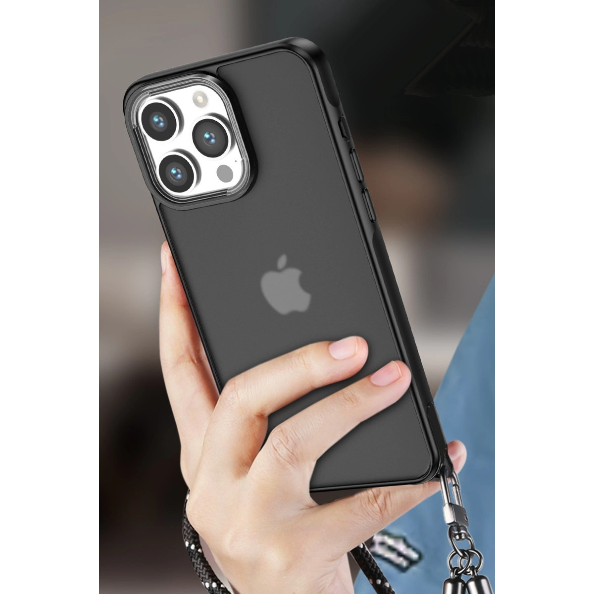 Bir el, şeffaf kılıflı siyah bir iPhone tutuyor. Arkada dört kamera.