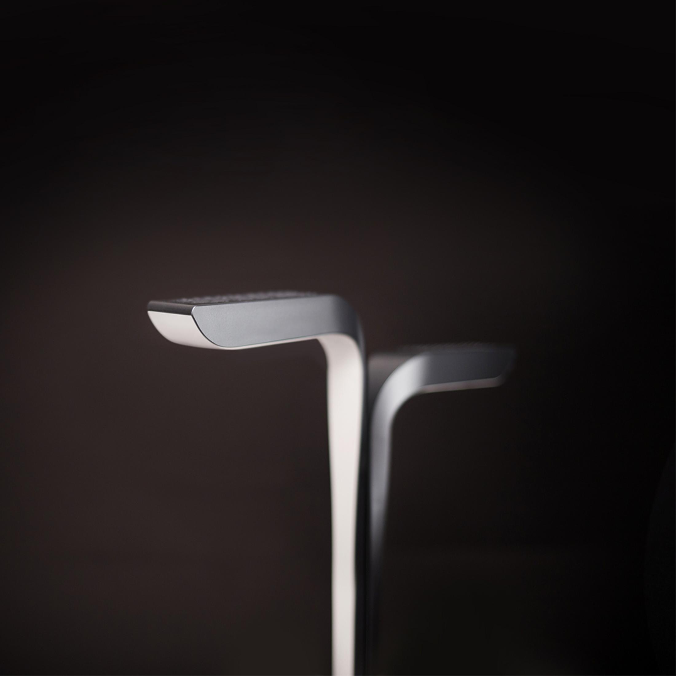 Detailansicht einer modernen, geschwungenen Tischlampe aus Metall und Kunststoff.