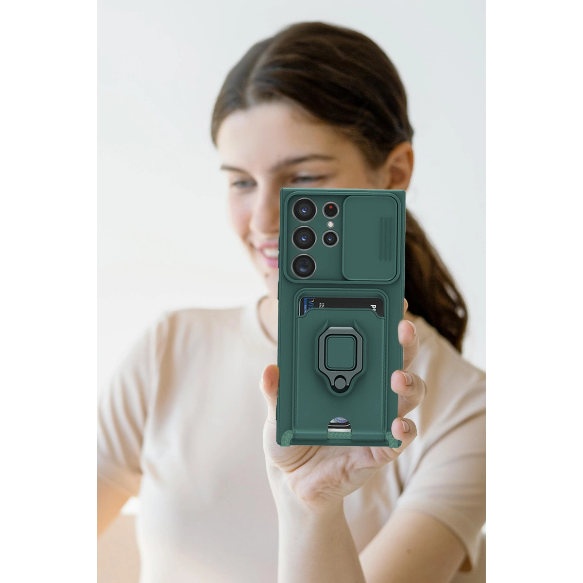 Kart yuvası ve halka tutuculu yeşil telefon kılıfı bir kadın tarafından tutuluyor.