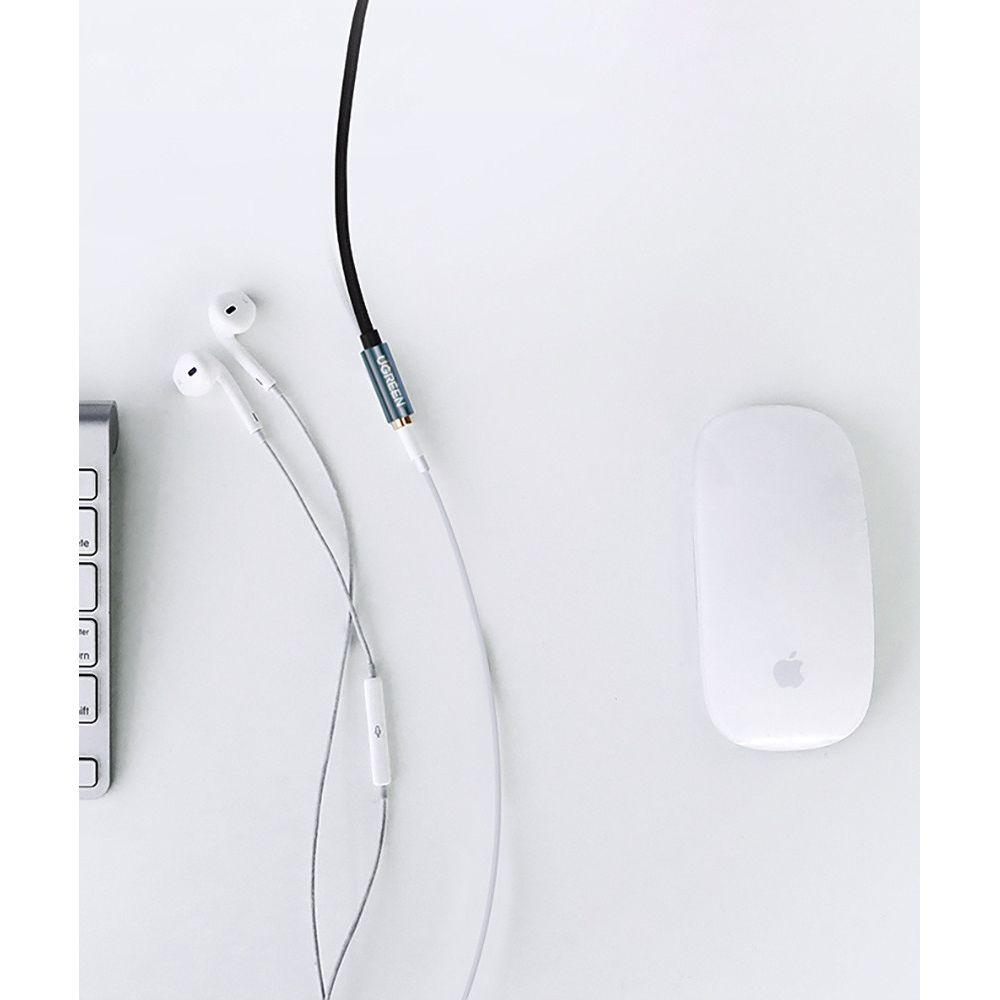 Biała mysz Apple, białe słuchawki i fragment klawiatury na białej powierzchni.